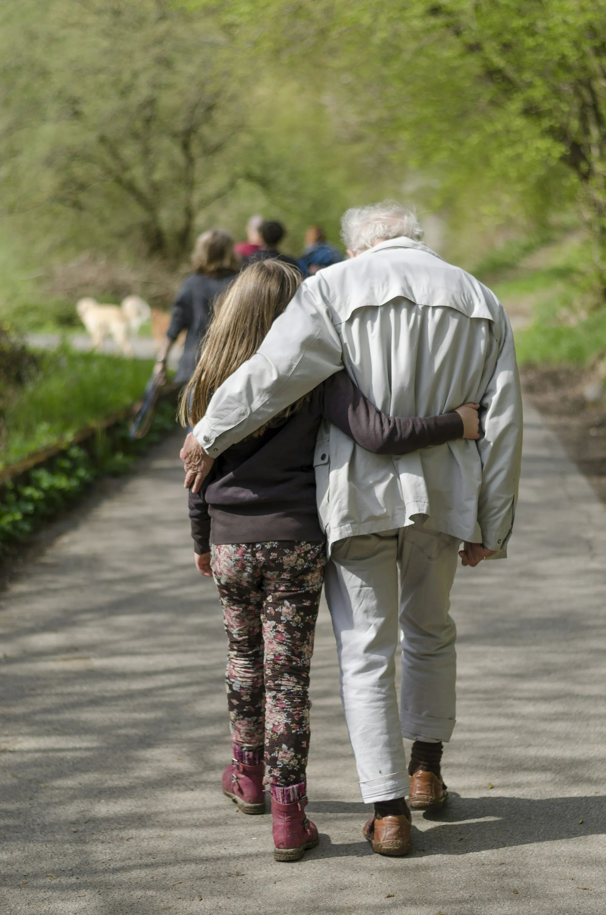 Child walking arm in arm with her grandfather