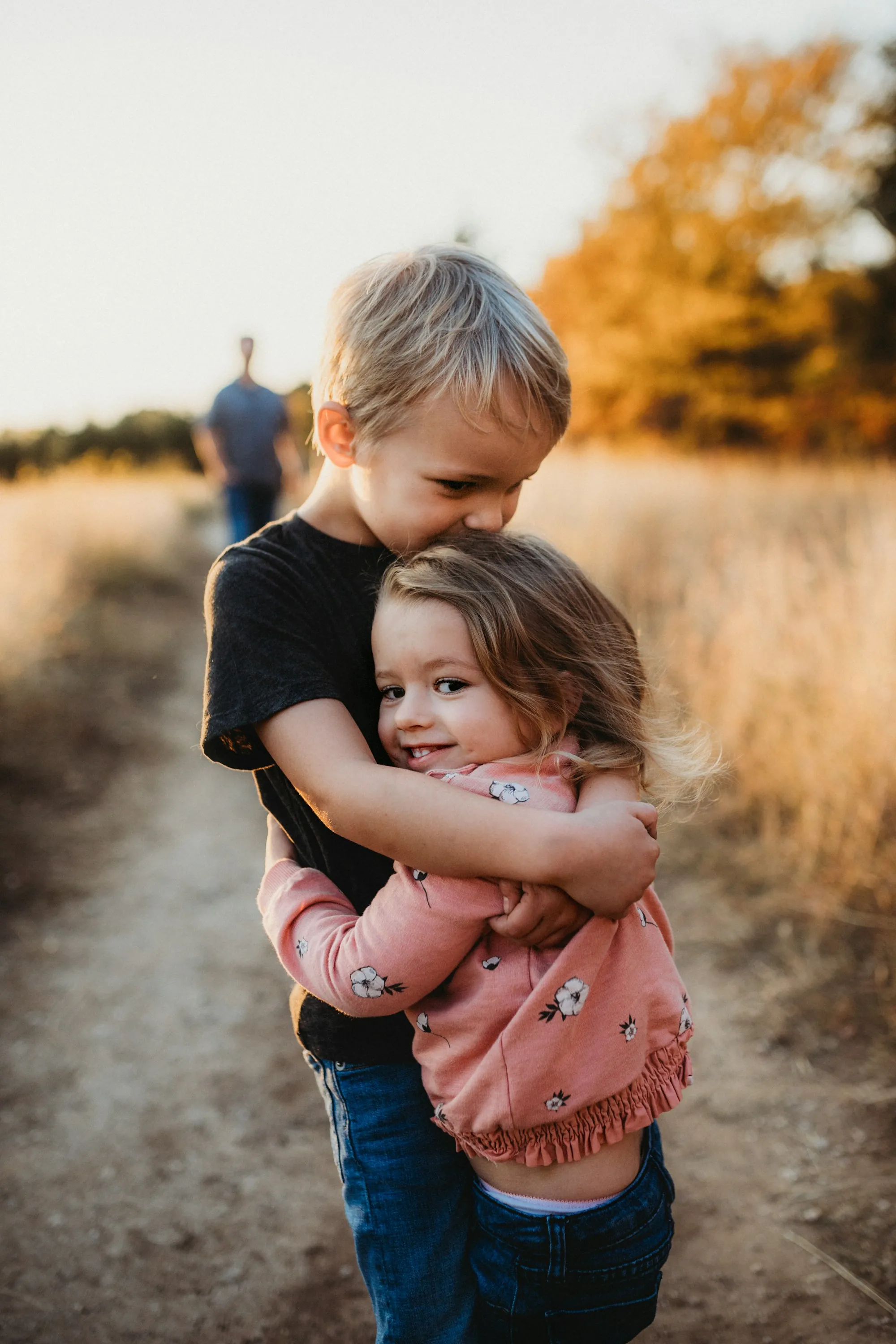 Older brother hugging his little sister in a golden field